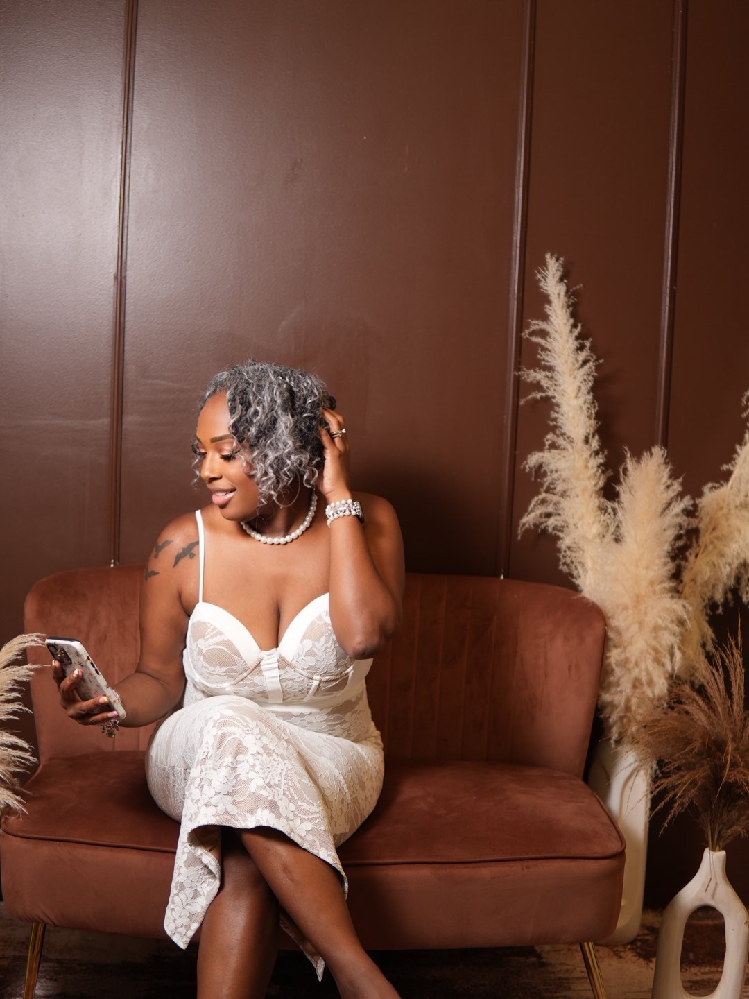 B. Johnson-Gray seated on a brown sofa in a white lace dress, smiling
